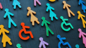 Diverse wooden figures representing gender, disability, and inclusion on a dark background