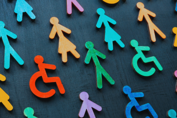 Diverse wooden figures representing gender, disability, and inclusion on a dark background