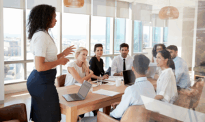 Businesswoman leading a boardroom discussion while others listen — symbolising Challenge in the Boardroom